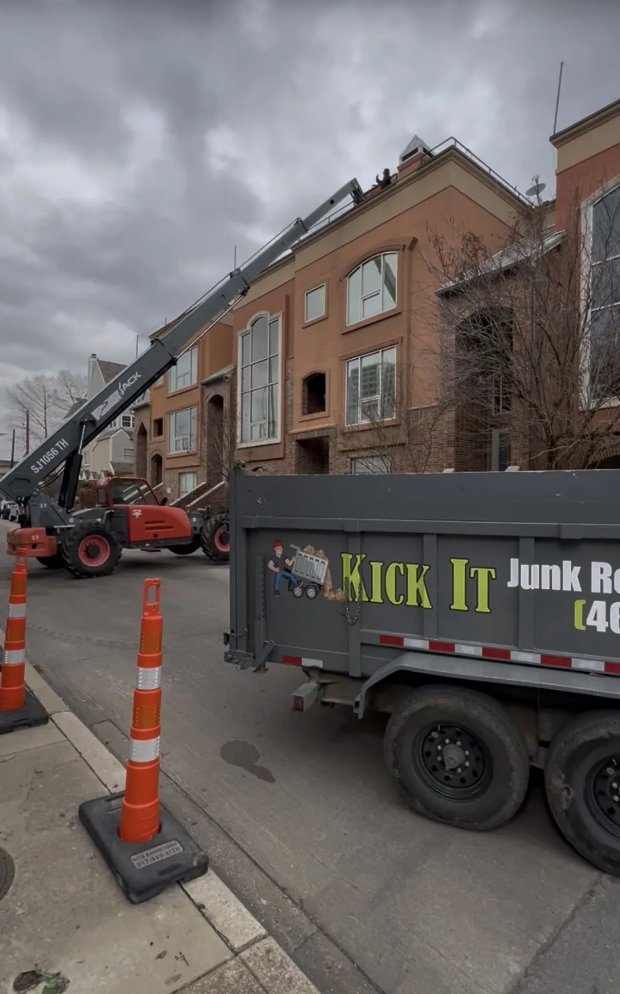 Crane-assisted rooftop deck removal with the Kick It trailer below
