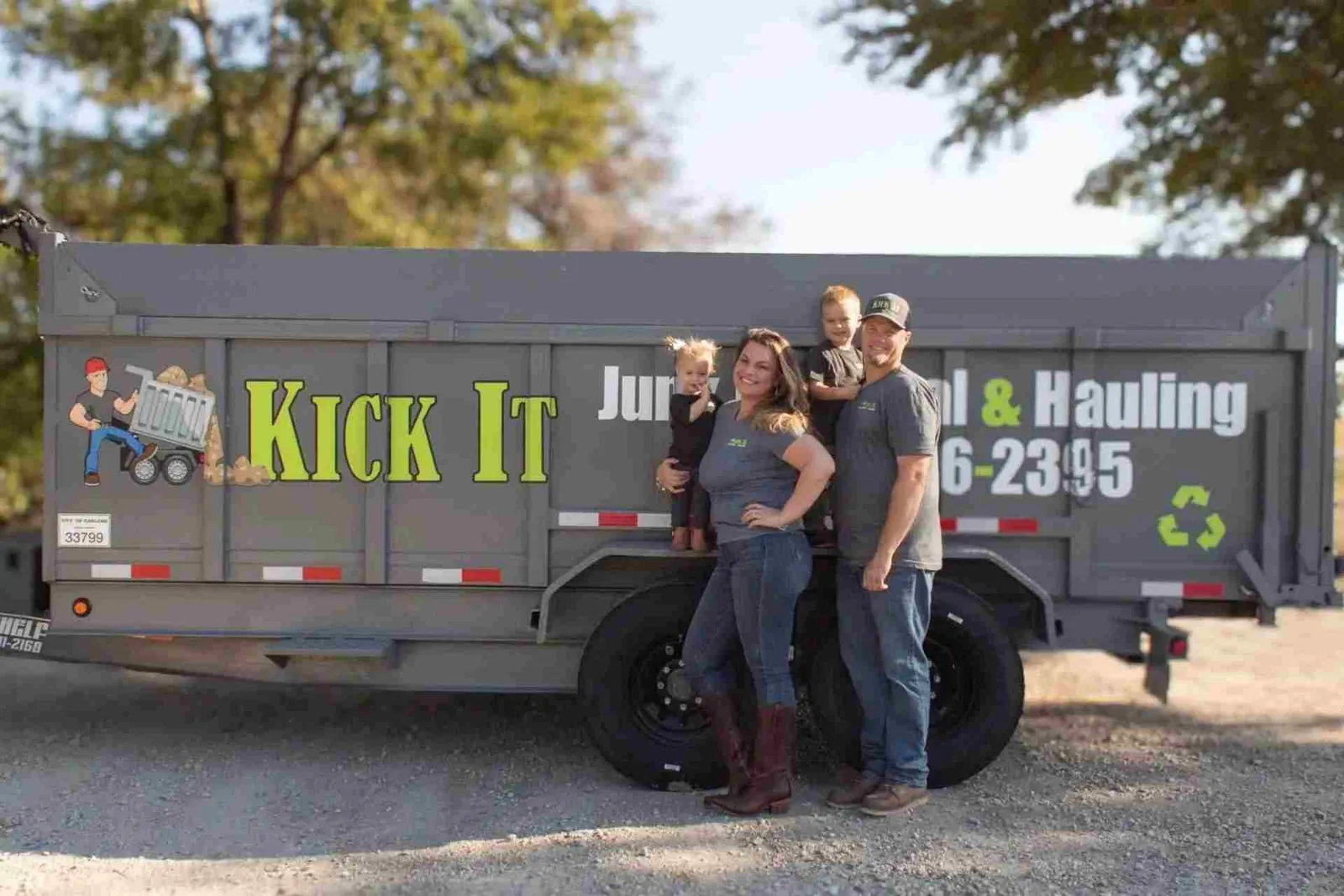 Paul and Jenifer Graham with their kids in front of the Kick It Junk Removal & Hauling trailer in Forney